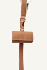Powder pink leather waste bag holder with rose gold hardware connected to a leash 
