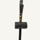 lack leather waste bag holder  with  gold hardware held by a hand on a white background