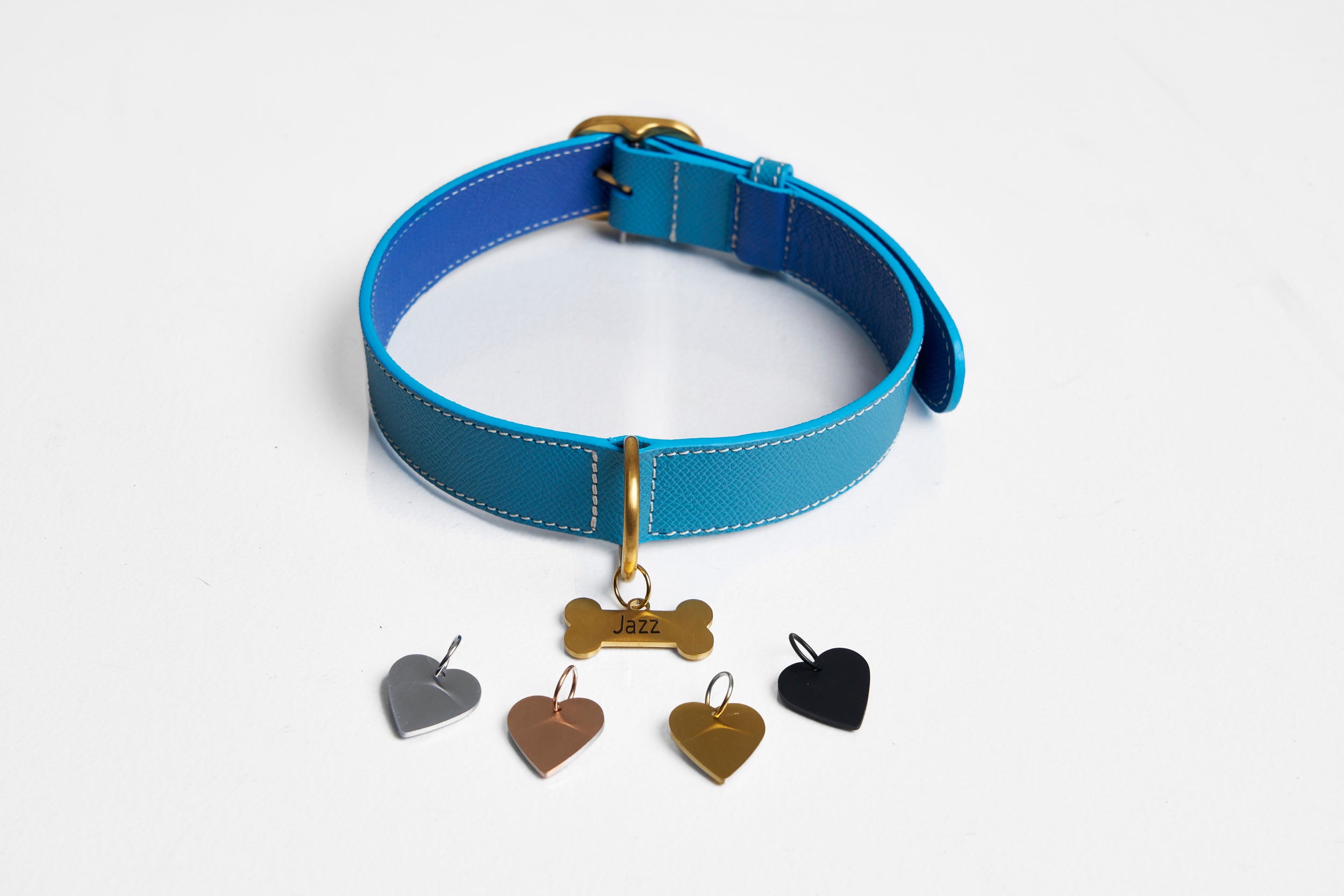 Blue leather collar with a gold bone dog tag and heart tags in four finishes