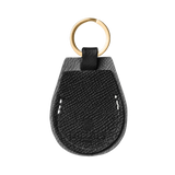 Black leather AirTag holder with gold hardware by Laelaps Paris